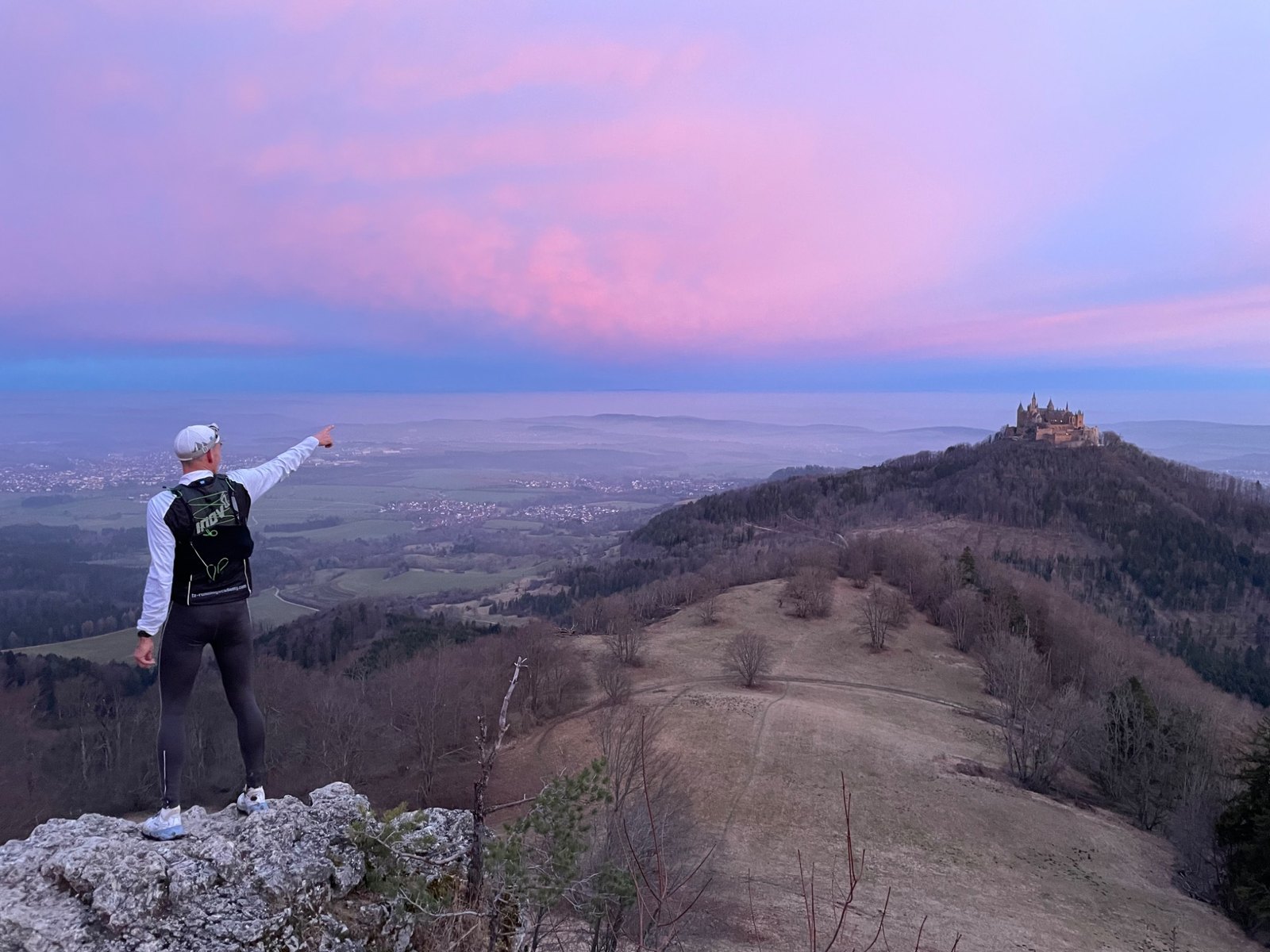 Läufer auf einem Felsen mit Blick auf die Burg Hohenzollern und den Zollernalbkreis