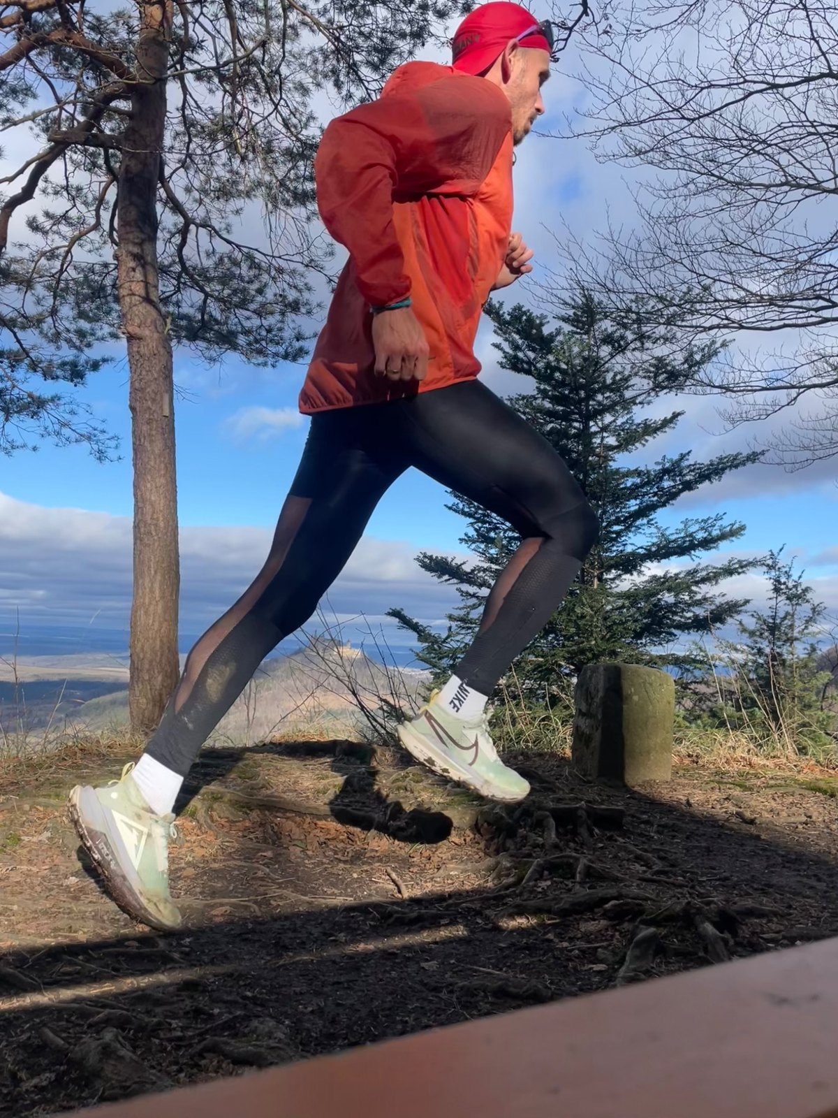 Läufer in roter Jacke beim Lauftraining auf einem Waldweg